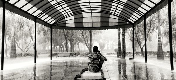 Rear view of man sitting on wall