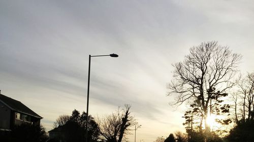 Low angle view of bare trees against sky at sunset