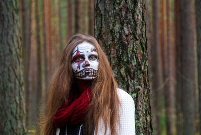 Portrait of spooky woman with halloween make-up standing in forest