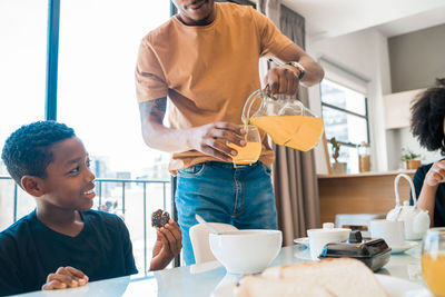 Family holding food on dining table at home