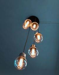 Low angle view of illuminated light bulbs hanging from ceiling