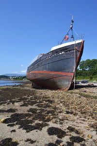 Boat moored on beach against clear sky