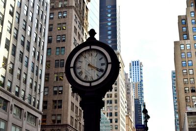 Low angle view of clock in city against sky