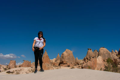 Man standing on rock against clear blue sky