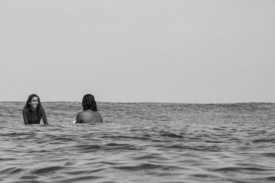 People swimming in sea against clear sky