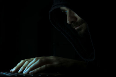 Computer hacker tying on keyboard against black background