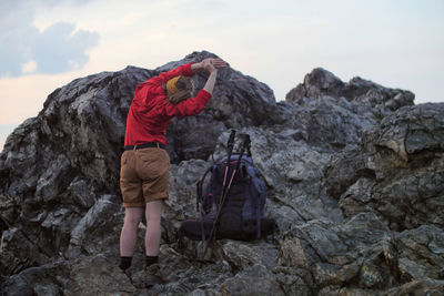 Man standing on rock against sky