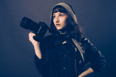 Young woman using mobile phone against blue background