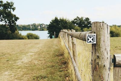 Sign on wooden post by road against sky