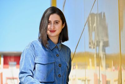 Portrait of smiling woman standing against blue sky