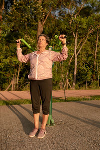 Full length of woman with arms raised standing on road