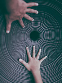 Close up of a father and son hands on a spiral textured chair