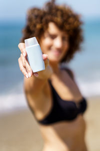 Midsection of woman using mobile phone at beach