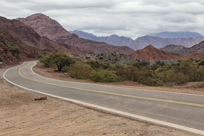 Scenic view of road by mountains against sky