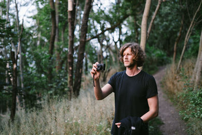 Young man photographing in forest