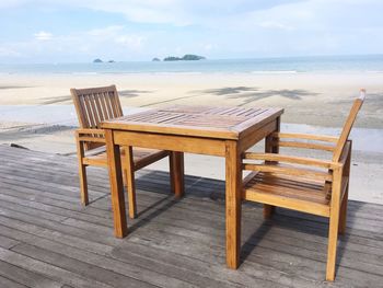 Chairs and table on beach against sky