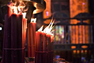 Close-up of lit candles in temple against building