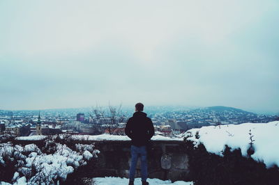 Rear view of man looking at cityscape during winter