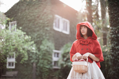 Portrait of young woman standing against plants