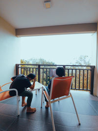 Rear view of woman sitting on chair at home