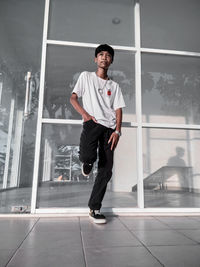 Full length portrait of young man standing against window