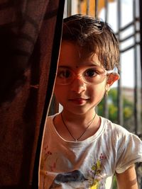 Portrait of cute girl wearing eyeglasses at home during sunset