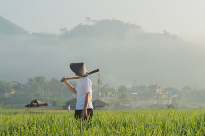 Side view of farmer wearing hat while standing on field