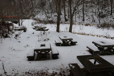 Empty bench on snow covered field during winter