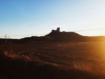 Scenic view of field against clear sky during sunset