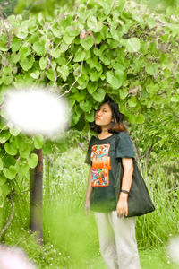 Young woman standing against plants