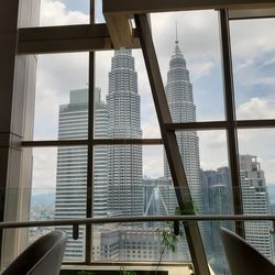 Modern buildings against sky seen through glass window