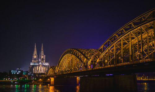 Low angle view of illuminated bridge over river at night