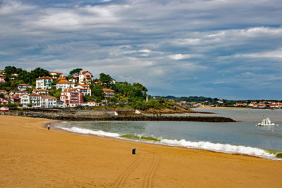 Scenic view of beach by buildings against sky