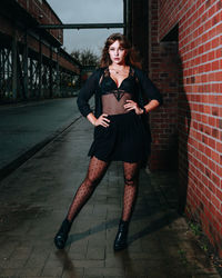 Portrait of young woman standing against brick wall