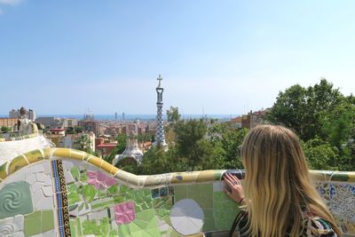 Woman looking at cityscape against sky