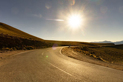 Empty road amidst landscape against sky