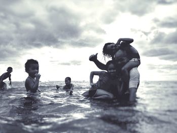 People on beach against cloudy sky