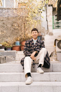 Portrait of young man sitting on staircase in city