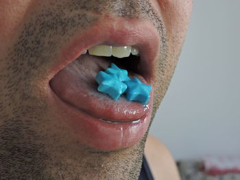 Close-up of man eating blue candies