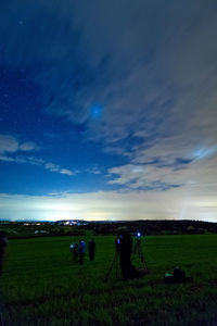 People on field against sky at night