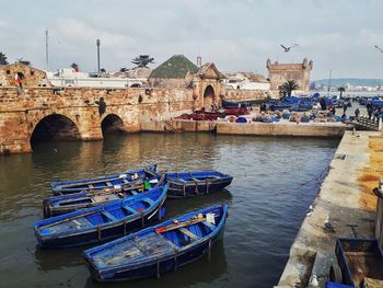 Boats moored in river with buildings in background