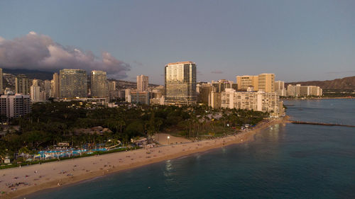 Buildings by sea against sky