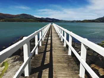 View of wooden bridge over sea against sky