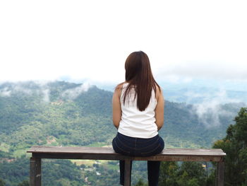 Rear view of woman sitting against mountain