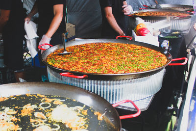 Midsection of men preparing food at market stall