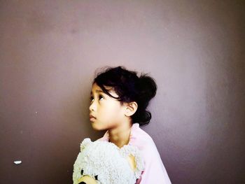 Portrait of a girl looking away against wall