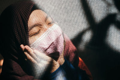 Young woman wearing mask with closed eyes