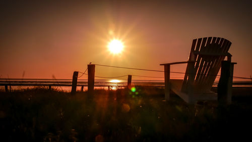 Silhouette railing by sea against sky during sunset