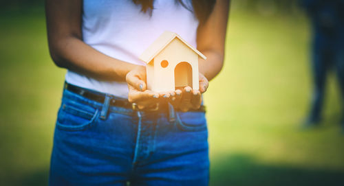 Midsection of woman holding model house