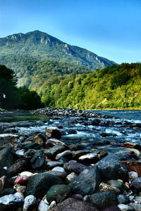 Scenic view of river by mountains against sky